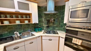 A modern kitchen with white cabinets, a stainless steel range hood, a built-in oven, and a gas stove.