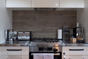 A modern kitchen with a Bosch gas stove, a KitchenAid toaster, a coffee maker, and a stainless steel refrigerator. - Elegant Urban Retreat in Freemans Bay. (Auckland)