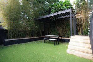 A garden with a wooden bench, a pergola, and a wooden deck. - Elegant Urban Retreat in Freemans Bay. (Auckland)