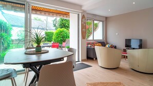 A modern living room with a dining area, a television, and a large window offering a view of the outdoors. - Ideally located in ST Pierre Quiberon, on the bay side. 200 meters from the beach, (Saint-Pierre-Quiberon)