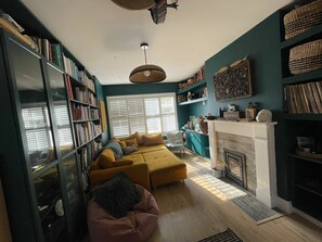 Una sala de estar acogedora con un sofá, una chimenea y una estantería llena de libros.
