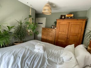 Ein Schlafzimmer mit einem Bett, einem Holzschrank und hängenden Pflanzen.