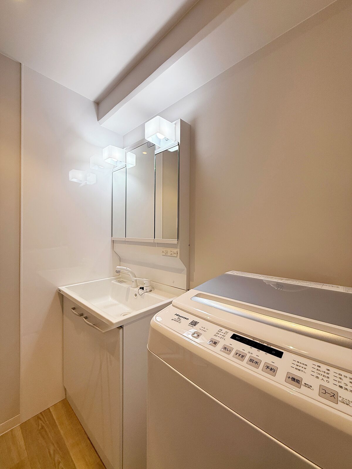Een kleine wasruimte met een wasmachine en een wasbak.