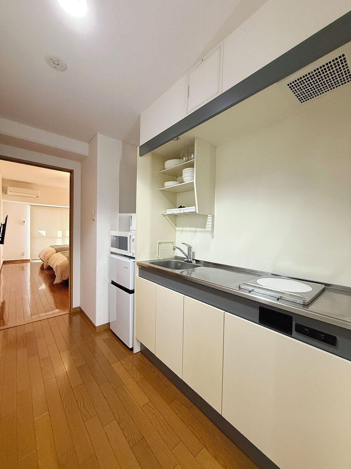 A modern kitchen with white cabinets, a stainless steel countertop, and a built-in microwave.