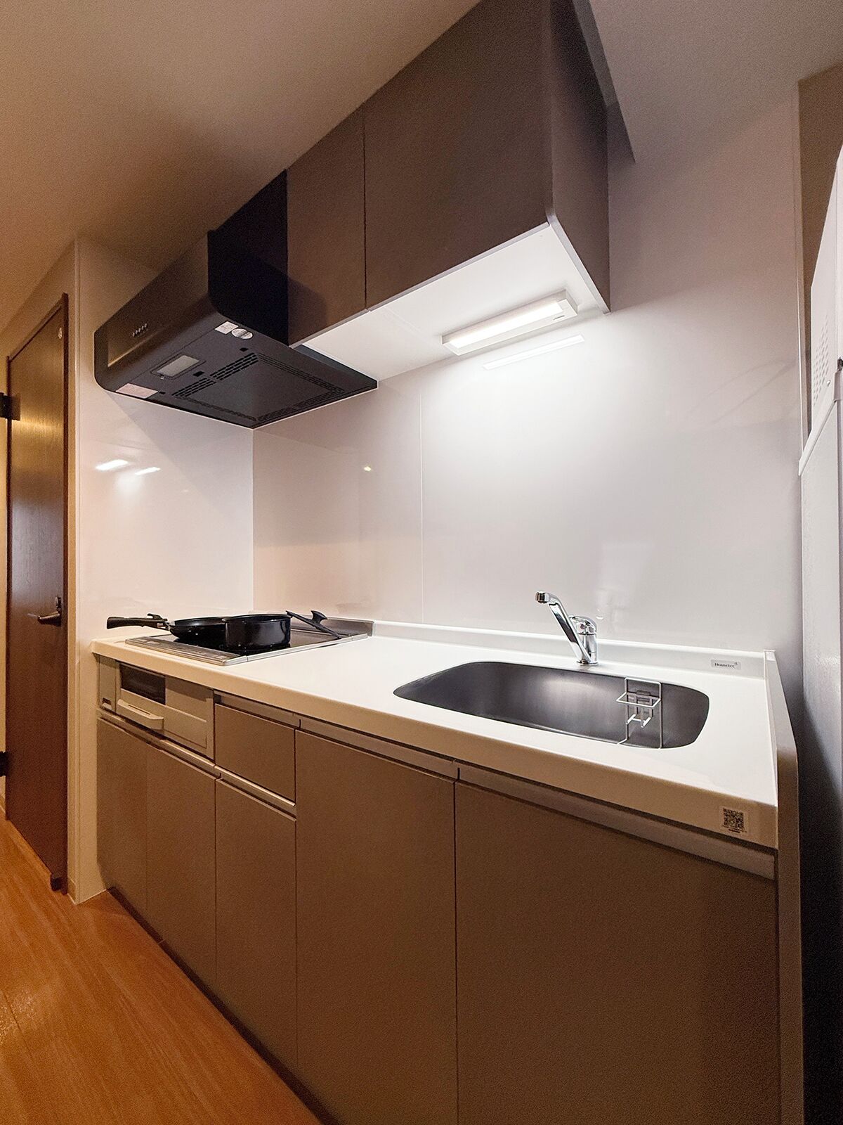 Una cocina moderna con estufa integrada, un fregadero y una campana extractora.