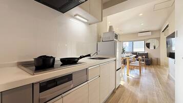 A modern kitchen with a built-in oven, microwave, and dishwasher. There is a dining area with a table and chairs, and a large window providing natural light.