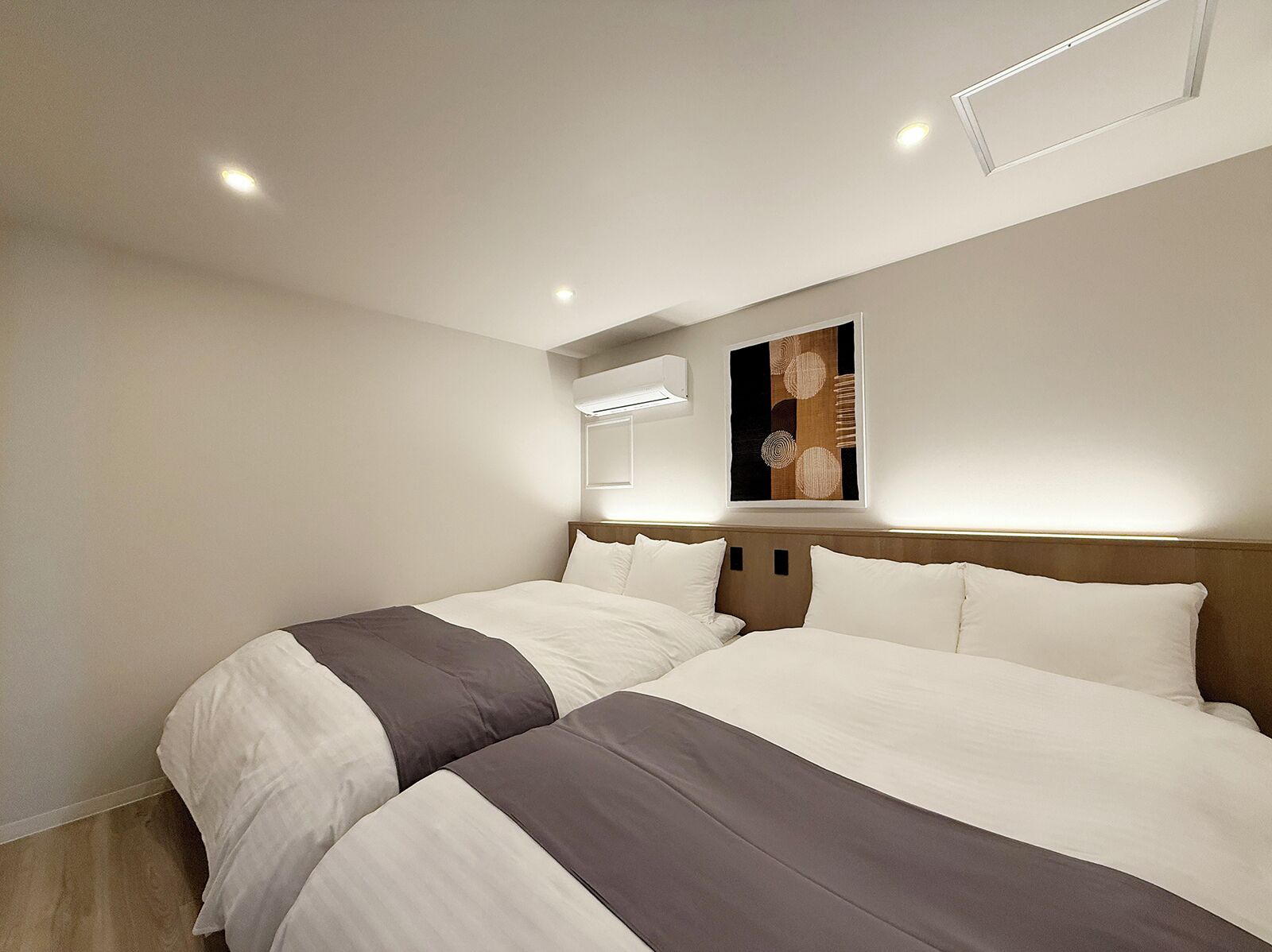 Habitación de hotel con dos camas, diseño moderno y un ventanal grande.