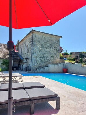 A stone building with a swimming pool, lounge chairs, and a red umbrella. - Charming renovated farmhouse with large pool (Lacour)