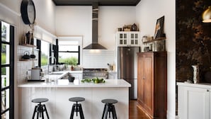 Une cuisine moderne dotée d’un îlot central, de tabourets de bar noirs, d’une grande cuisinière et d’un réfrigérateur.