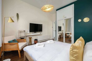 Een hotelkamer met een bed, een televisie, een stoel, een klein tafeltje en een spiegel.