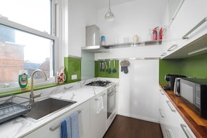 A compact kitchen with a gas stove, a sink, and a microwave.
