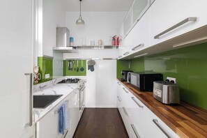 Una cocina compacta equipada con estufa a gas, microondas, tostadora y cafetera.