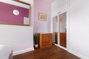 Una habitación con un aparador de madera, un espejo, un cuadro enmarco y una puerta corredera.