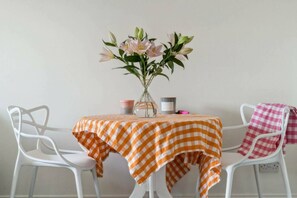 A table with a checkered tablecloth, a vase with flowers, and a candle on the table. - Stylish & Elegant 1 bed flat - Watford (Hertfordshire)