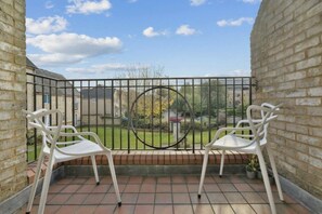 A balcony with two white chairs, a metal railing, and a view of a garden and houses in the background. - Stylish & Elegant 1 bed flat - Watford (Hertfordshire)