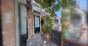 A cafe terrace with outdoor seating, a chalkboard menu, and a sign indicating the cafe is open.