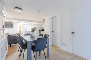 A modern kitchen with white cabinets, a dining table with chairs, and a white door.