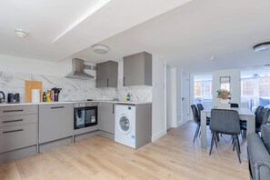 Een moderne keuken met een ingebouwde oven, wasmachine en grijze kastjes.