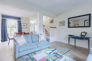 A living room with a sofa, coffee table, and a staircase. - Refined 2BD Flat Between Westminster and Chelsea (Greater London)