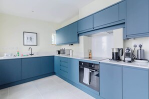 Eine moderne Küche mit blauen Schränken, einer Mikrowelle, einer Kaffeemaschine und einem Geschirrspüler.