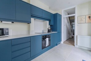 A modern kitchen with blue cabinets, a microwave, and a stove.