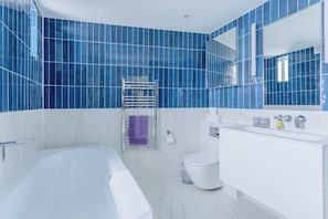 A modern bathroom with a bathtub, toilet, and white vanity.