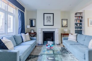A living room with two sofas, a fireplace, a coffee table, and a bookshelf.