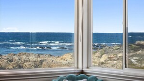 A room with a large window overlooking a rocky coastline and the ocean. - 3976 Beach House on Asilomar~ Oceanfront View Home (Pacific Grove)