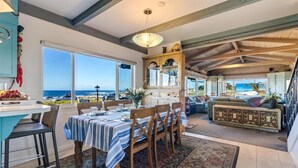 A dining area with a view of the ocean, a kitchen with a large window, and a living area with a sofa and a view of the beach. - 3976 Beach House on Asilomar~ Oceanfront View Home (Pacific Grove)