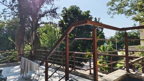 Una escalera con barandales de metal, un área de descanso techada y vistas de la vegetación y edificios circundantes.