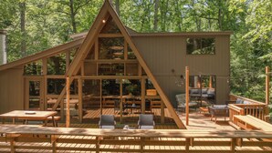 Een chalet met een houten terras, grote ramen en een eethoek.