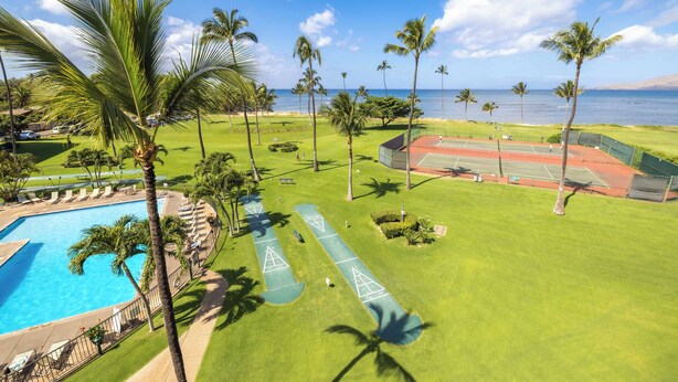 A golf course with a swimming pool, palm trees, and a view of the ocean.