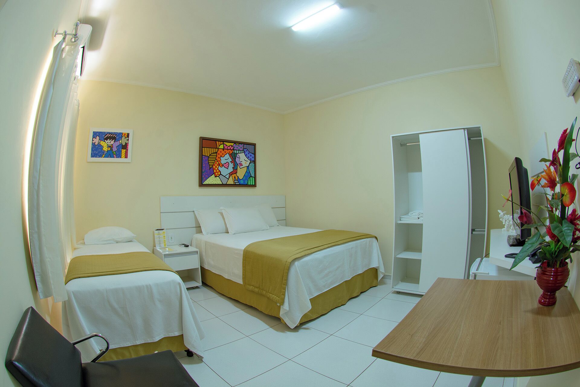 Habitación de hotel con dos camas, un escritorio, un armario y un cuadro en la pared.