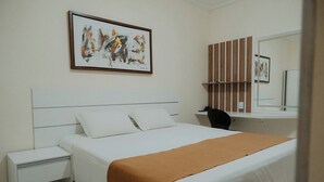 A neatly arranged bedroom with a bed, bedside table, and a desk with a chair. - Araripina Palace Hotel (Araripina)