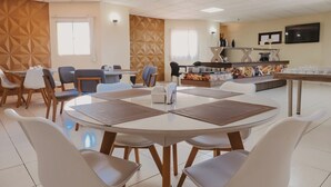 A modern dining area with round tables and chairs, a buffet counter, and a geometric patterned wall. - Araripina Palace Hotel (Araripina)