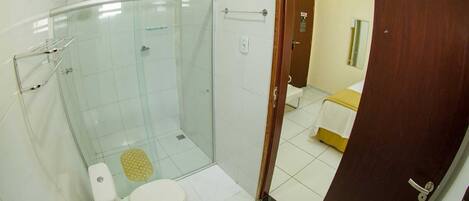 Un baño con ducha de mampara de vidrio, inodoro y lavamanos.