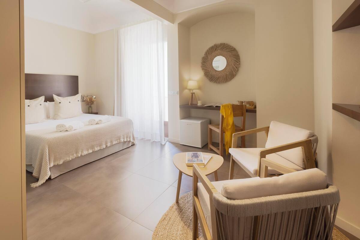 Ein Hotelzimmer mit einem Bett, einem Schreibtisch, einem Sessel und einem runden Tisch.