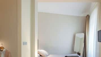 A hotel room with a bed, a bedside lamp, a mirror, and a TV.