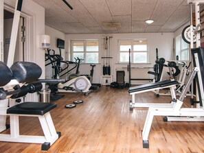 Een sportschool met diverse fitnessapparaten, waaronder loopbanden, krachttrainingsmachines en gewichten.