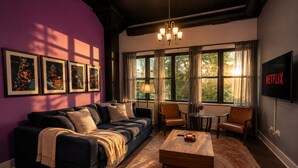 A living room with a sofa, coffee table, and chairs, a TV, and framed pictures on the wall. - Stylish 2BR Cozy South Loop Suite  Near McCormick (Chicago)