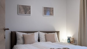 A neatly made bed with a striped white and beige duvet, two pillows, and a brown blanket. There are two framed artworks on the wall above the bed. - Apartment in Schwaz Near Kellerjoch Ski Area (Schwaz)