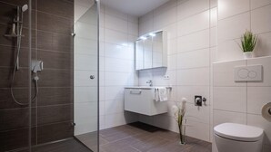 A modern bathroom with a glass shower enclosure, a white toilet, a vanity with a mirror, and a potted plant. - Apartment in Schwaz Near Kellerjoch Ski Area (Schwaz)