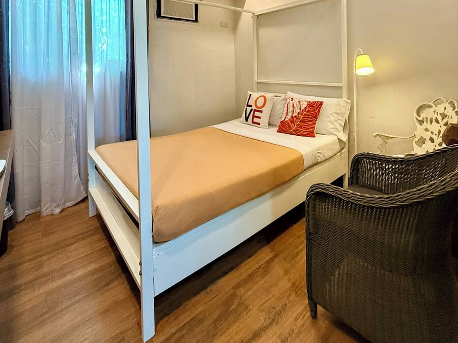 Une chambre avec un lit à baldaquin, une chaise, une lampe et une fenêtre avec des rideaux.