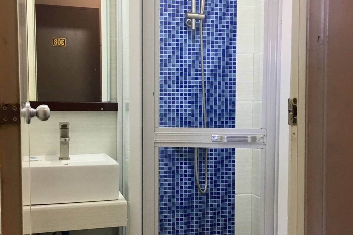 A bathroom with a glass-enclosed shower, a white sink, and a toilet.