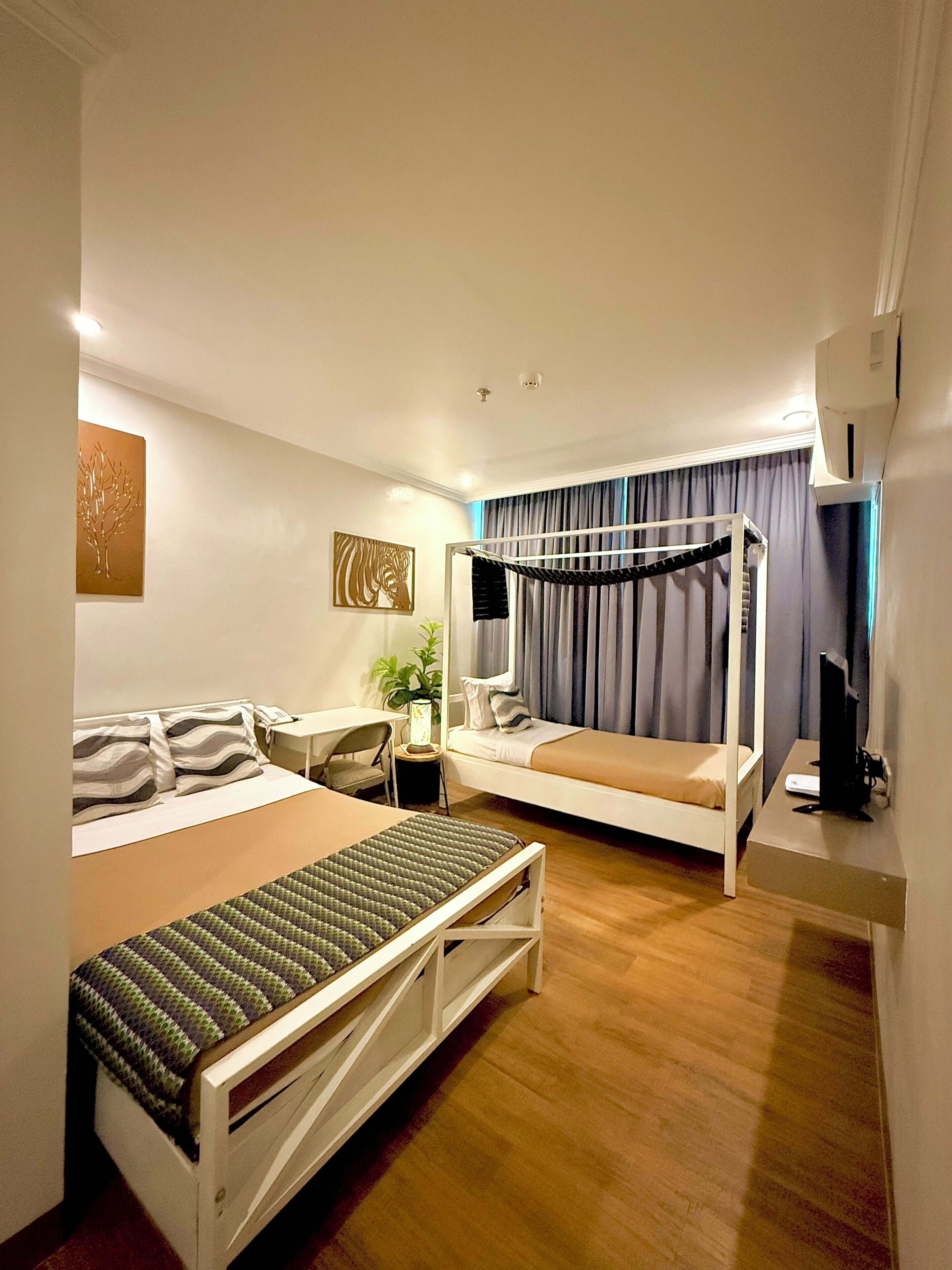 Una habitación de hotel moderna con literas, un escritorio, una silla, una mesita de noche y un televisor.