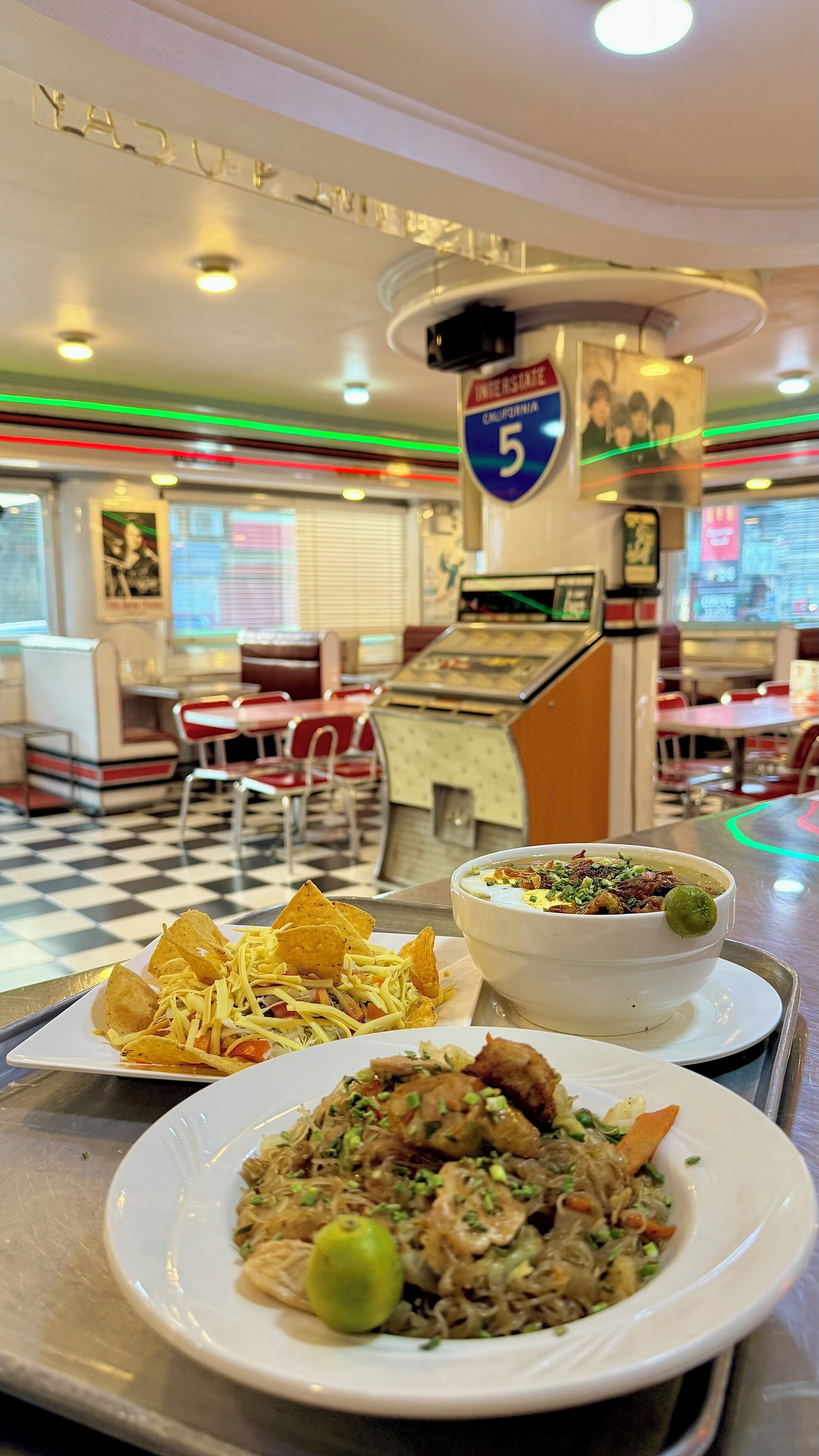 A diner interior with a checkered floor, booths, a counter with a menu, and a sign for Interstate 5.