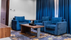 A modern living room with a blue sofa set, a wooden coffee table, and a patterned rug. - ALHYAT Hotel (Jeddah)