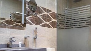 A modern bathroom with a marble vanity, a large mirror, a shower with a glass door, and a toilet. - ALHYAT Hotel (Jeddah)