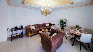 A living room with a brown sofa, a round coffee table, and a dining area with a table set for four.