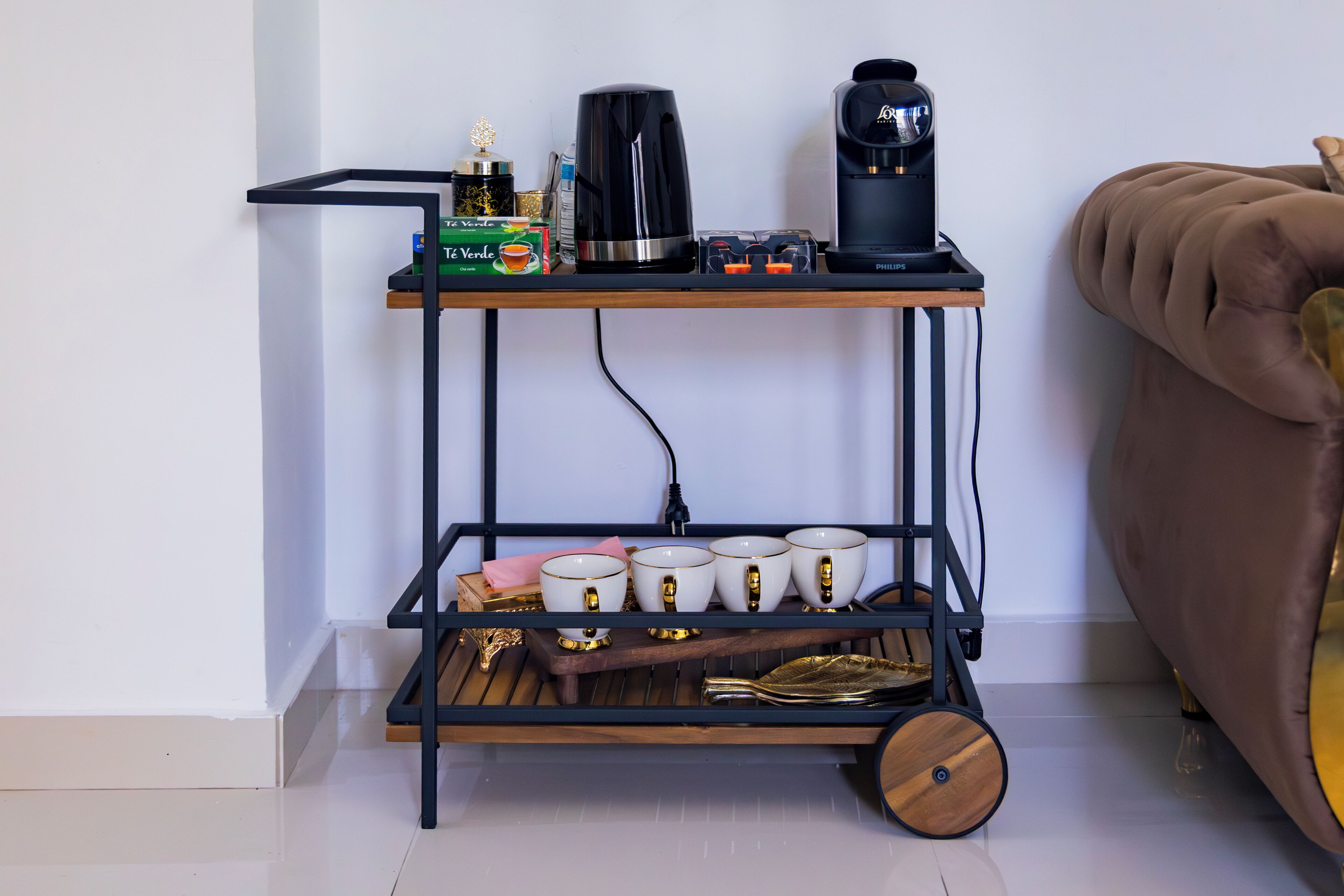 Um espaço com café, uma cafeteira, chávenas e uma caixa de chá.